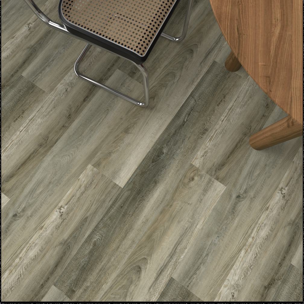 Gray-brown wood-look vinyl plank flooring shown from an overhead angle, with parts of a chair and a wooden table visible in the scene.